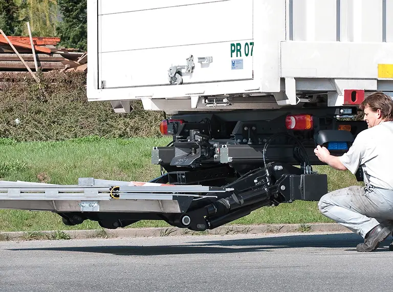 A Palfinger retractable tail lift extended during inspection, with hydraulic components visible.