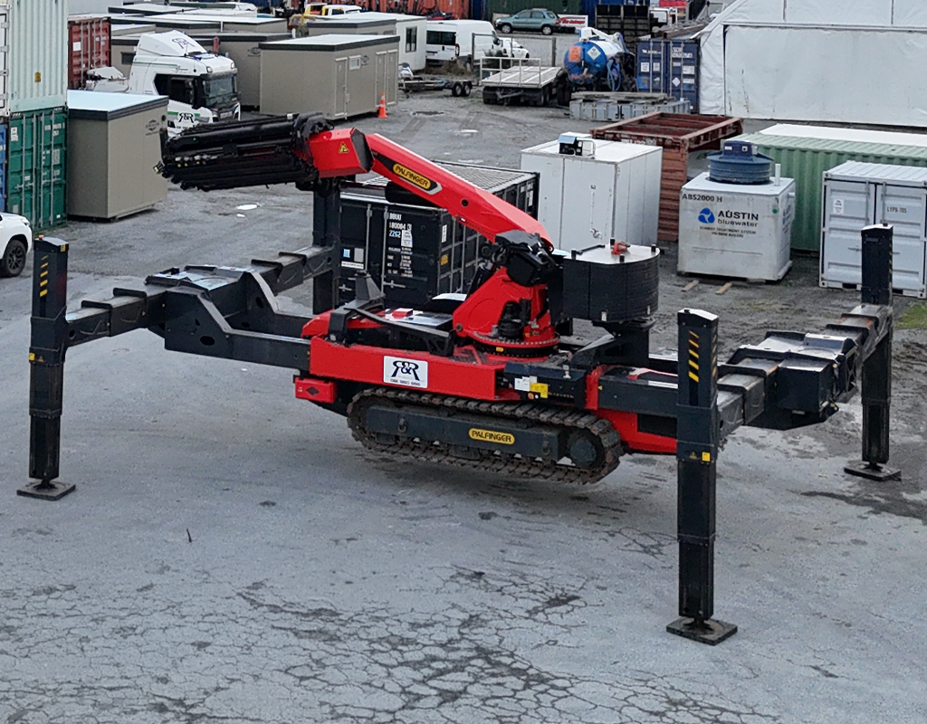 PALFINGER PCC115 crawler crane travelling over uneven terrain with outriggers folded for transport.